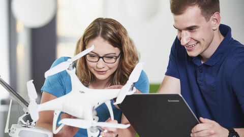 Zwei Studierende arbeiten an einer Drohne.