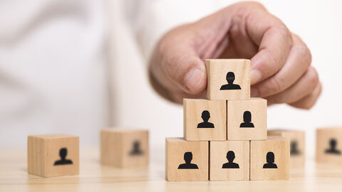 Hand baut Pyramide mit Holzwürfeln.